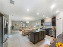 Open-concept living area with a central island kitchen, tile flooring, and great natural light at 15120 Zenith Ave, Mascotte, FL 34753