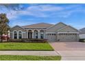 Charming home featuring arched entryways, a well-maintained lawn, and a spacious three-car garage at 15993 Johns Lake Overlook Dr, Winter Garden, FL 34787