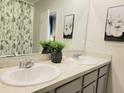 Well-lit bathroom featuring double sinks, neutral countertops, and decorative wall art at 333 Jovana Rd, Davenport, FL 33837