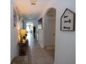 Inviting hallway featuring tiled floors, decorative wall art, and archways leading to other rooms at 3332 Logan Berry Dr, Mount Dora, FL 32757