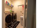 Efficient laundry room with modern washer and dryer set, storage shelves, and a laundry-themed rug at 3332 Logan Berry Dr, Mount Dora, FL 32757