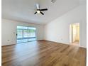 Main bedroom featuring wood-look floors, ceiling fan, and sliding glass doors to the enclosed lanai at 10238 Summit Square Dr, Leesburg, FL 34788