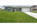 Inviting single-story home featuring a well-manicured lawn, attached garage, and a classic neutral exterior color at 13220 Sw 85Th Pl, Ocala, FL 34473