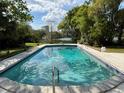 Inviting backyard pool with clear blue water, set against a backdrop of mature trees and a serene lakeside view at 321 E Copeland Dr, Orlando, FL 32806