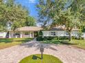 Charming single-story home with manicured lawn, circular brick driveway, mature trees, and white shutters at 5205 Saint Regis Pl, Belle Isle, FL 32812