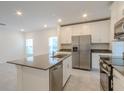 Modern, open-concept kitchen featuring an island, stainless steel appliances, and white cabinetry at 6140 Shavasana Rd, Clermont, FL 34714