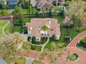 An aerial view of a luxury home highlighting its tile roof, manicured garden, and circular driveway at 9224 Bentley Park Cir, Orlando, FL 32819