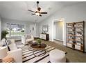 Inviting living room with vaulted ceiling, neutral decor and natural light from large windows at 15525 Seymour Ln, Groveland, FL 34736