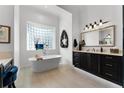 Serene bathroom featuring a modern standalone tub, glass block window, and dark wood vanity with stone countertops at 1613 Glenwick Dr, Windermere, FL 34786