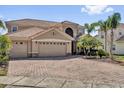 Elegant two-story home featuring a three-car garage, tile roof, and paver driveway at 2020 Imperial Eagle Pl, Kissimmee, FL 34746