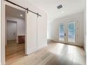 Bright foyer featuring stylish barn door, frosted glass doors, and hardwood flooring at 3206 Harrison Ave, Orlando, FL 32804