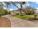 View of home and long driveway, mature trees, and landscaped lawn at 37 Spring Ln, Haines City, FL 33844