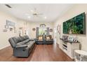 Inviting living room with hardwood floors, ceiling fan, a large TV, and comfortable seating at 37 Spring Ln, Haines City, FL 33844