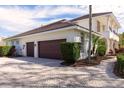 Side view of a house with a three-car garage and a brick-paved driveway and walkway at 8661 Crestgate Cir, Orlando, FL 32819