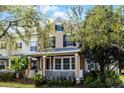 Charming tan two-story home with black shutters, welcoming front porch with white railings and mature tree and landscape features at 9228 Cardinal Meadow Trl, Orlando, FL 32827