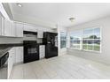Well-lit kitchen with white cabinets, black appliances, granite counters, and a breakfast nook area at 13254 Boulder Woods Cir, Orlando, FL 32824