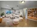 Bright living room featuring tile floors, white furniture with striped pillows, and a ceiling fan at 4561 Evers Pl, Orlando, FL 32811