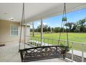 Inviting covered front porch with a swing overlooking a large field at 735 Deerfoot Rd, Deland, FL 32720