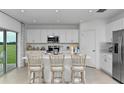 Modern kitchen with stainless steel appliances, white cabinets, and a large island with bar seating at 7392 Capstone Dr, Groveland, FL 34736
