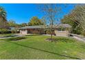 Charming single-story home featuring a well-manicured lawn, mature trees, and a welcoming front porch at 10031 Union Park Dr, Orlando, FL 32817