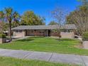 Charming single-story home featuring a well-manicured lawn, mature trees, and a welcoming front porch at 10031 Union Park Dr, Orlando, FL 32817