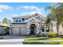 Charming two-story home with stone accents, gray exterior, and well-manicured front lawn at 10699 Petrillo Way, Winter Garden, FL 34787