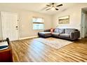 Bright living room featuring hardwood floors, a comfortable gray sofa, and a large window with natural light at 1197 Village Forest Pl, Winter Park, FL 32792