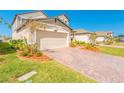 Paver driveway and a two-car garage with landscaped front yard in a suburban neighborhood at 125 Links Terrace Blvd, Daytona Beach, FL 32124