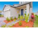 Home's front porch with stone accents, a blue front door, and colorful landscaping at 125 Links Terrace Blvd, Daytona Beach, FL 32124