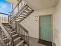 Exterior view of stairwell and unit door with teal trim, unit number and matte black handrailings at 2230 Cascades Blvd # 104, Kissimmee, FL 34741