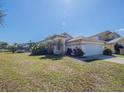 Charming single-story home featuring a two-car garage, tropical landscaping, screened pool, and lush green lawn at 3100 Tall Grass Pl, Kissimmee, FL 34743