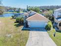 Aerial view of a well-maintained single-story home with a two-car garage, screened pool, and waterfront access at 3100 Tall Grass Pl, Kissimmee, FL 34743