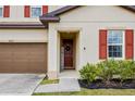 Close up of the front door showing brick red shutters, matching door and a brown two car garage at 5607 Western Sky Pl, St Cloud, FL 34771