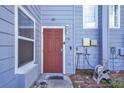 Close-up of a light blue townhouse entrance with a red front door and tidy landscaping at 758 Orchid Dr, Davenport, FL 33897