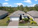An aerial view of a well-maintained home with lush landscaping, a brick driveway, and a serene, wooded backdrop at 1121 Avery Meadows Way, Deland, FL 32724