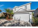 Gray two-story home boasts a lush, tropical landscaped yard and a spacious two-car garage at 14415 Estrella Dr, Orlando, FL 32837