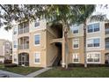 Exterior view of a tan apartment building with two palm trees and stairs to the units at 2304 Silver Palm Dr # 103, Kissimmee, FL 34747