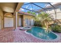 Inviting screened-in pool and spa area surrounded by brick pavers and mature landscaping at 2442 Heritage Green Ave, Davenport, FL 33837