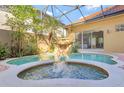Beautiful screened-in pool area with a tranquil waterfall feature and lush greenery at 2442 Heritage Green Ave, Davenport, FL 33837