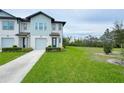 Inviting townhome with attached garage, surrounded by green lawns and complemented by mature trees, under a partially cloudy sky at 1549 Discovery St, Davenport, FL 33896