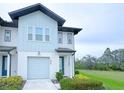 Attractive townhome featuring an attached garage, complemented by manicured landscaping and lush green lawns at 1549 Discovery St, Davenport, FL 33896