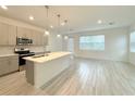 Open-concept kitchen featuring stainless steel appliances, a large island, stylish pendant lighting, and sleek gray cabinetry at 1549 Discovery St, Davenport, FL 33896