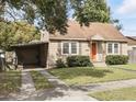 Charming single-story home with a well-manicured lawn, complemented by a quaint orange front door at 1975 Staunton Ave, Winter Park, FL 32789