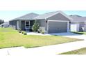 Inviting single-story home featuring a manicured lawn, gray exterior, and a two-car garage at 2294 Sunset Way, Davenport, FL 33837