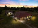 Dusk view of a single-story house with red roof; the windows are lit, and it has an attached carport and a separate outbuilding at 2730 W Highland St, Lakeland, FL 33815