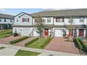 Inviting townhome with a one car garage, red door and shutters, and manicured lawn at 319 Smugglers Way, Apopka, FL 32712