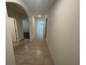 Inviting hallway with tiled floor leading to bright living spaces, arched entryways, and neutral walls at 956 Brooklet Dr, Davenport, FL 33837