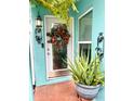 Close up of the front door that features a decorative wreath, sidelight, and potted plant at 11213 River Grove Dr, Orlando, FL 32817