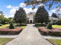 Elegant home features mature trees, manicured lawns, and a paved driveway in a lush, daytime setting at 11306 Bridge House Rd, Windermere, FL 34786