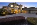 Luxury home boasts manicured bushes, a circular driveway, and warm lighting accentuating the facade at 11306 Bridge House Rd, Windermere, FL 34786